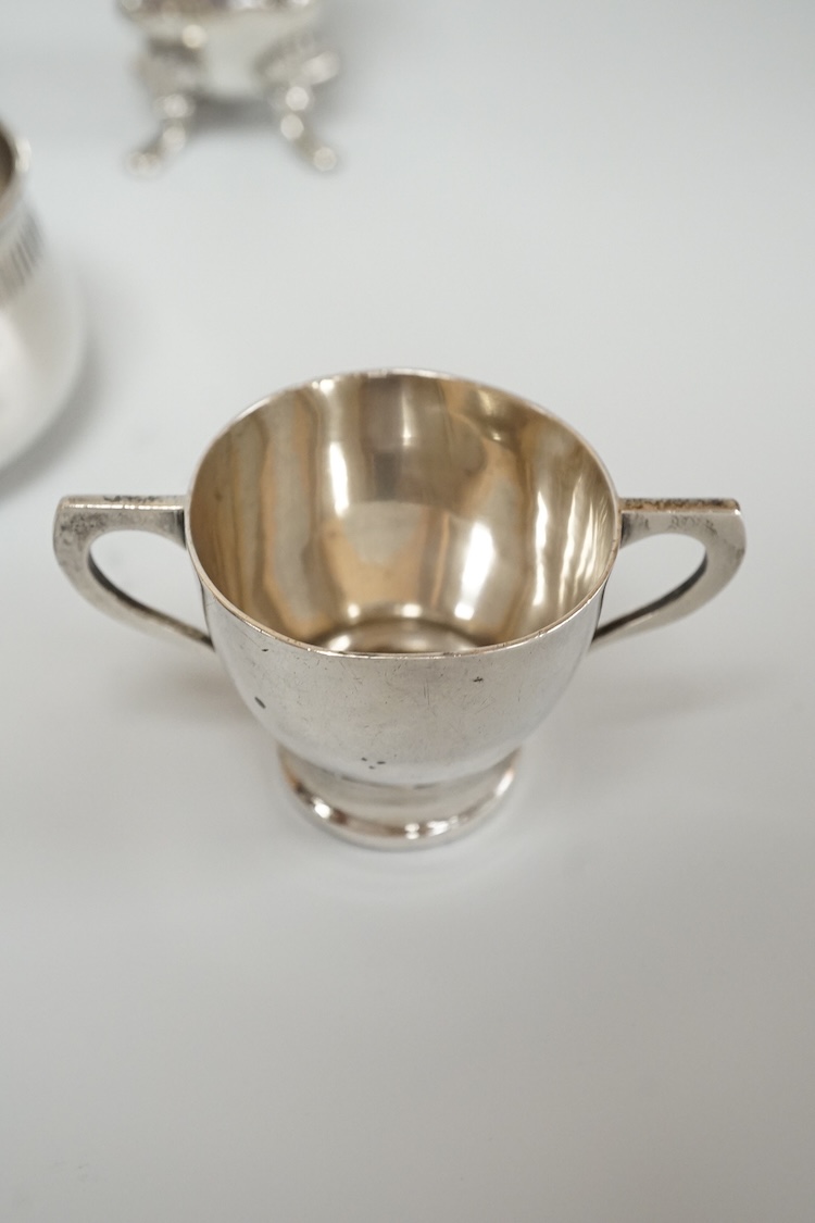 Four assorted silver condiments including a Victorian bun salt and a late Victorian pepper mill, together with a small silver bowl, a silver matchbox sleeve and a small silver two handled cup.